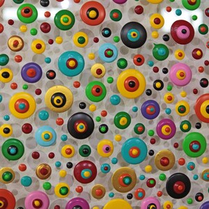 May include: A white background with a variety of colorful circles with black centers. The circles are arranged in a random pattern and are of different sizes.