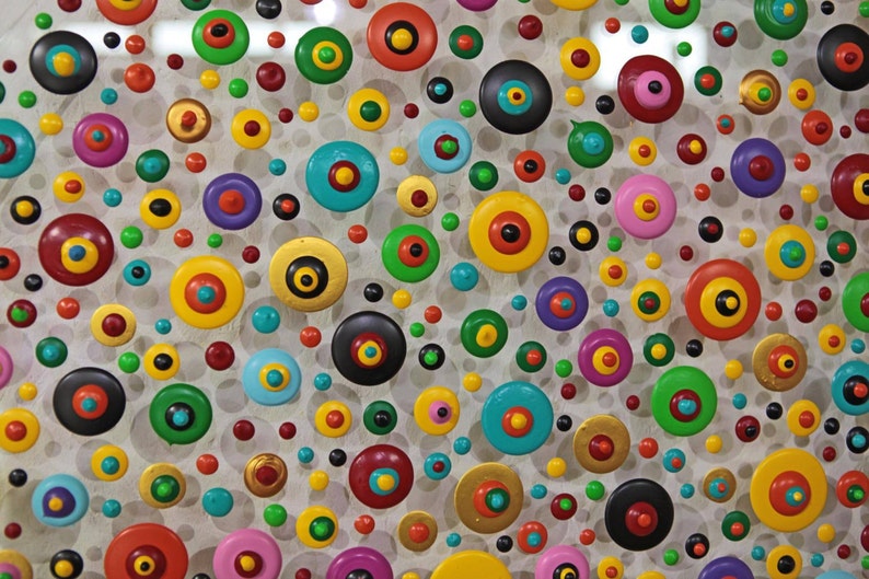 May include: A white background with a variety of colorful circles with black centers. The circles are arranged in a random pattern and are of different sizes.
