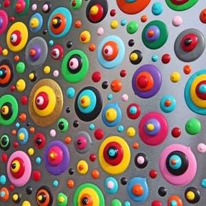 May include: A silver background with a pattern of colorful circles with concentric rings. The circles are in various sizes and colors, including red, yellow, blue, green, and purple.
