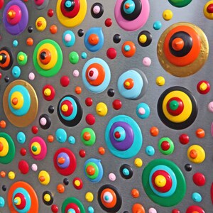 May include: Abstract painting with a silver background and colorful circles with concentric rings. The circles are painted in various colors, including red, blue, green, yellow, and pink.