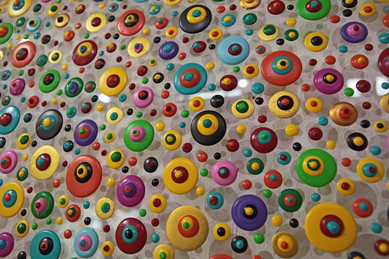 May include: A close-up of a colorful abstract art piece featuring a variety of round shapes with different colors and patterns. The shapes are arranged in a random pattern on a white background.