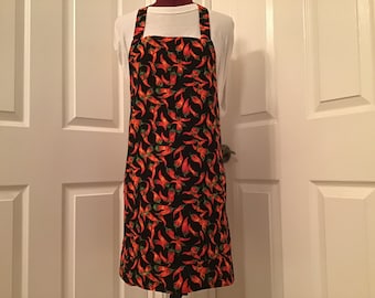 May include: A black apron with a red and green chili pepper pattern. The apron has adjustable straps and a large pocket.