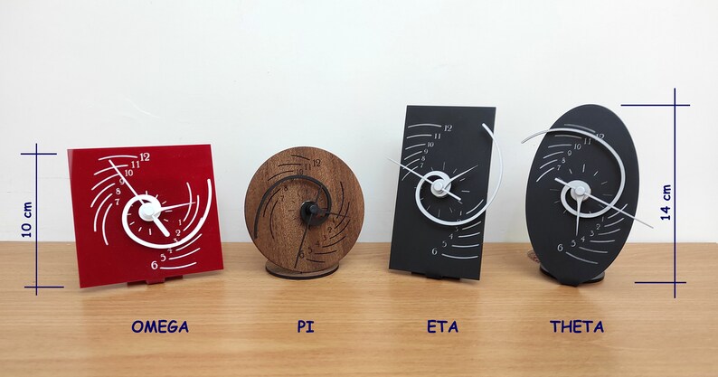 Op de afbeelding: Vier verschillende stijlen van spiraalvormige klokken, elk met een uniek ontwerp. De klokken zijn gelabeld "OMEGA", "PI", "ETA" en "THETA". De klokken zijn 10 cm breed en 14 cm hoog.