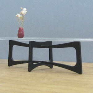 May include: A modern coffee table with a clear glass top and a black metal base. The base has a unique curved design.