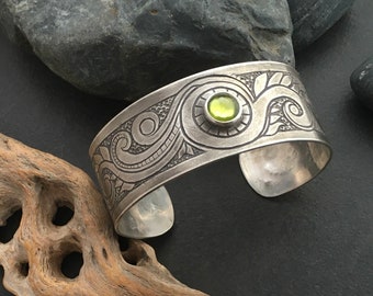 Sterling silver cuff bracelet, wide, hand engraved with a scroll work pattern, deep grey patina and set with bright green peridot gemstone