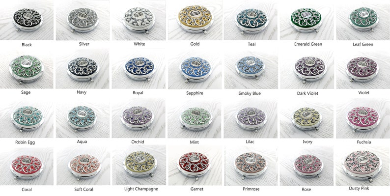 May include: A collection of 24 compact mirrors with ornate silver frames and various colored enamel inlays. The mirrors are arranged in four rows of six, with each row featuring a different color scheme.