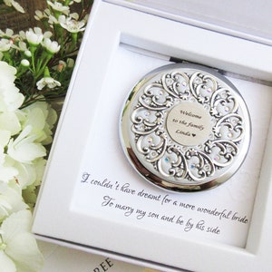 May include: A silver compact mirror with an ornate design and rhinestones. The mirror is in a white box with a message that reads "Welcome to the family Linda".