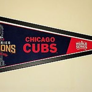 Puede incluir: Un banderín enmarcado con fondo azul y detalles en rojo, blanco y azul. El banderín presenta el logotipo de los Chicago Cubs, el texto "World Series Champions" y el texto "Chicago Cubs".