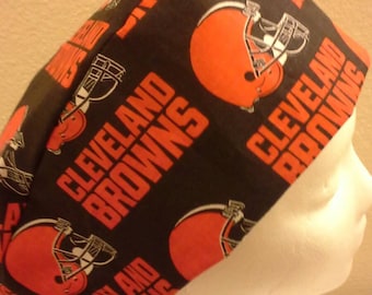 May include: A black scrub hat with a repeating pattern of orange and white Cleveland Browns logos. The hat has a tie on the back.