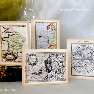 May include: Four vintage maps printed on cream-colored paper with black frames. The maps are of France, Ireland, a region of Ireland, and a world map. The maps are all in black and white with some color accents.