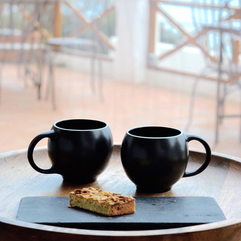 Black stoneware ceramic Eva teacups in smooth high-fired stoneware by Maia Ming Designs, inspired by Eva Zeisel. Tactile, sculptural form for mindful tea rituals and quiet mornings,for tea enthusiasts and design-conscious interiors.