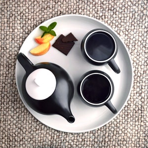 Top view of Eva teapot and teacups by Maia Ming Designs, high-fired porcelain with a tactile sculptural form inspired by Eva Zeisel. Modern minimalist design for mindful daily rituals, perfect for interior styling, boutique hotel tables, or contemplative tea moments.