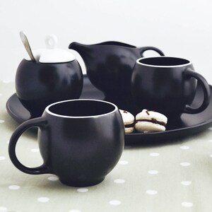 Close-up of the Eva teacup and other teaware by Maia Ming Designs, highlighting its smooth tactile form and sculptural curves.