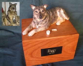 May include: A wooden pet urn with a sculpted dog figurine on top. The urn has a black plaque with the name "Ziggy" and the dates "2003-2015".