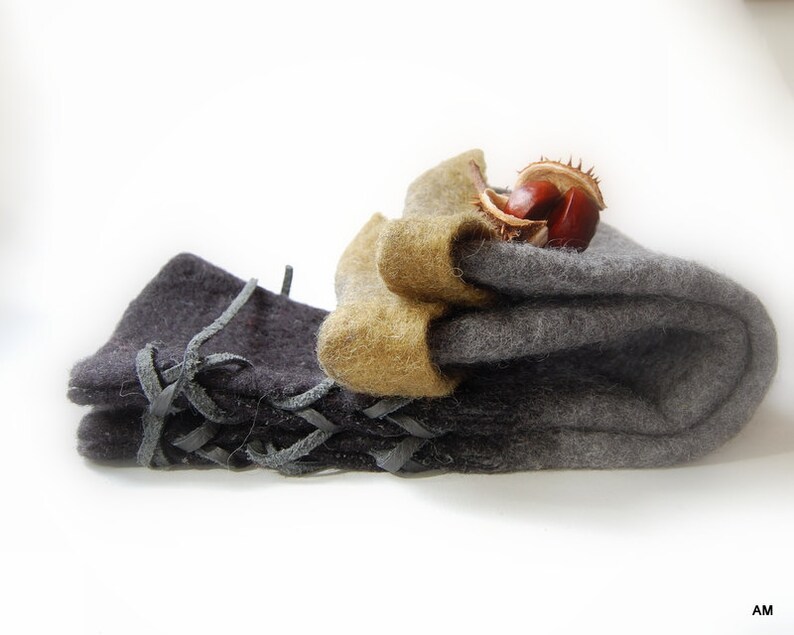 May include: Two pairs of felted wool fingerless gloves. One pair is gray and the other is black with leather lacing. The gray pair has a brown chestnut on top.