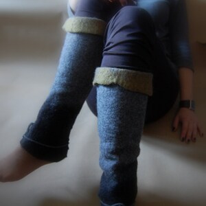 May include: A pair of blue and gray leg warmers with a brown cuff. The leg warmers are made of a soft, knitted fabric.