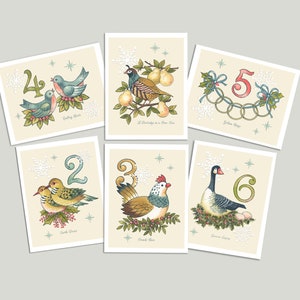 May include: Six illustrated cards featuring the Twelve Days of Christmas. Each card features a number, a bird or animal, and a phrase from the song. The cards are on a cream background with snowflakes and stars.