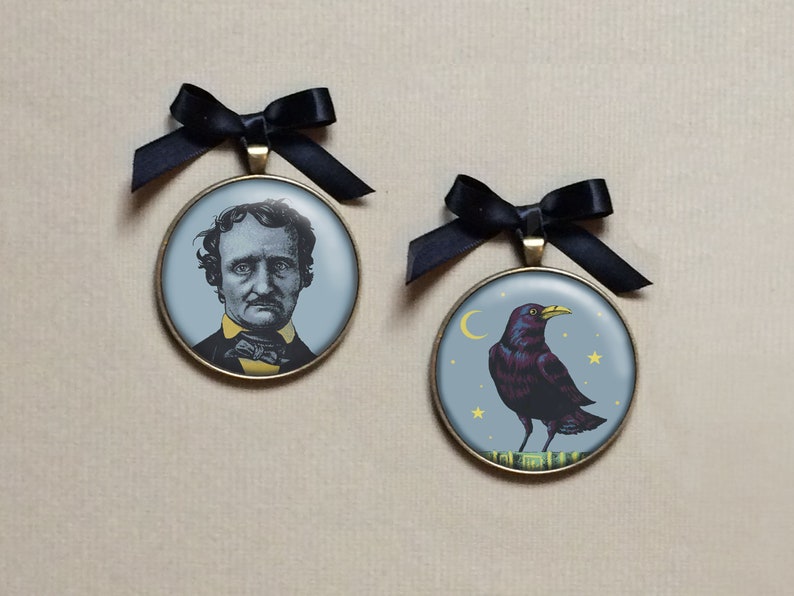 May include: Two round, bronze-colored ornaments with black ribbon hangers. The first ornament features a black and white portrait of Edgar Allan Poe. The second ornament features a black raven with a yellow beak and yellow stars on a blue background.