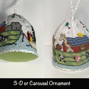 May include: A 3-D or Carousel ornament featuring a white fabric base with a colorful embroidered scene of animals on a boat. The ornament has a green felt bottom and a white cord for hanging.