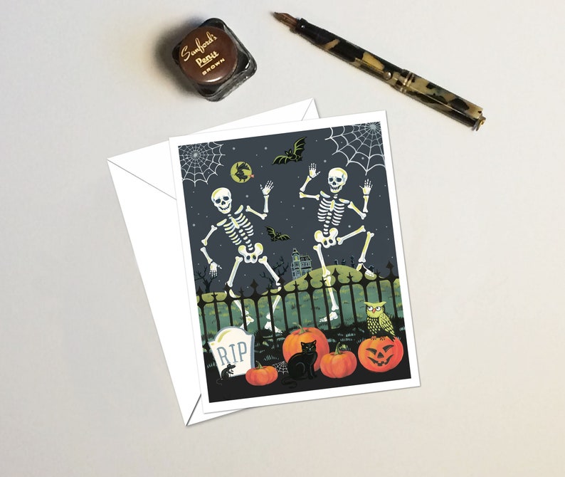May include: A Halloween greeting card featuring two skeletons dancing in front of a spooky fence with a graveyard behind them. There are pumpkins, a black cat, and an owl in the foreground.