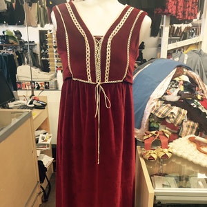 Puede incluir: Un vestido largo de color burdeos con ribete de encaje. El vestido tiene un escote en V y un lazo en la cintura.