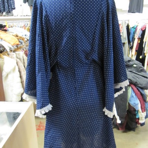 May include: A navy blue dress with white polka dots and white lace trim on the sleeves. The dress has a long, flowing skirt and a fitted bodice.