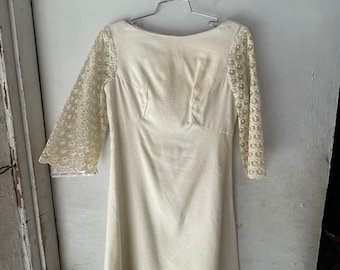 May include: A white vintage dress with lace sleeves. The dress has a scoop neckline and a simple, A-line silhouette.