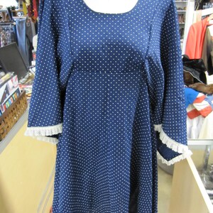 May include: A blue and white polka dot dress with a scoop neck and 3/4 sleeves. The sleeves have white lace trim.