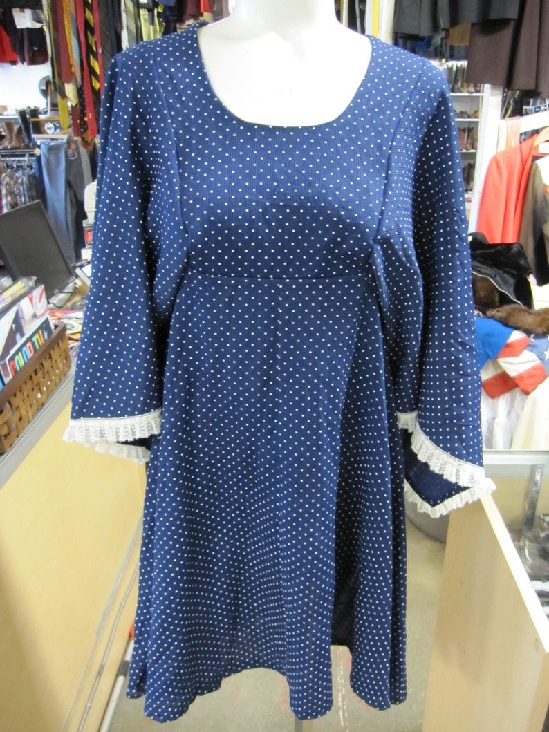 May include: A blue and white polka dot dress with a scoop neck and 3/4 sleeves. The sleeves have white lace trim.