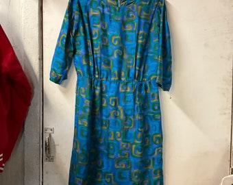 Puede incluir: Un vestido estampado azul y verde con cintura fruncida. El vestido tiene un escote redondo y mangas tres cuartos.
