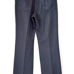 May include: A pair of dark blue denim jeans with a straight leg fit. The jeans have a classic five-pocket design with a button fly.