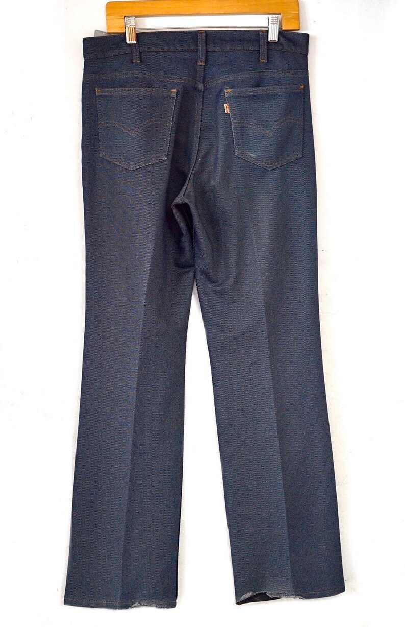 May include: A pair of dark blue denim jeans with a straight leg fit. The jeans have a classic five-pocket design with a button fly.