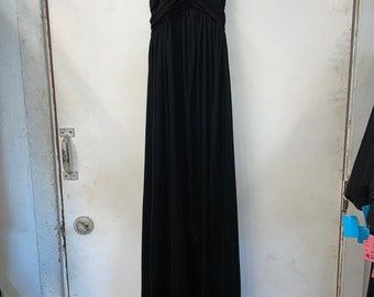 Può includere: Un abito maxi nero con scollo a halter, un corpetto drappeggiato e una gonna fluida.