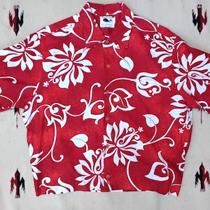 May include: A red button-down shirt with a white floral pattern. The short-sleeved shirt features a classic collar and a relaxed fit. The shirt is made of a lightweight fabric, perfect for warm weather. The shirt has a small whale logo on the collar.