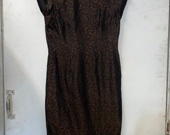 May include: A brown and gold cheongsam dress with a floral pattern. The dress has a mandarin collar and short sleeves.