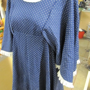 May include: A blue and white polka dot dress with a white lace trim on the sleeves. The dress has a scoop neck and a loose fit.