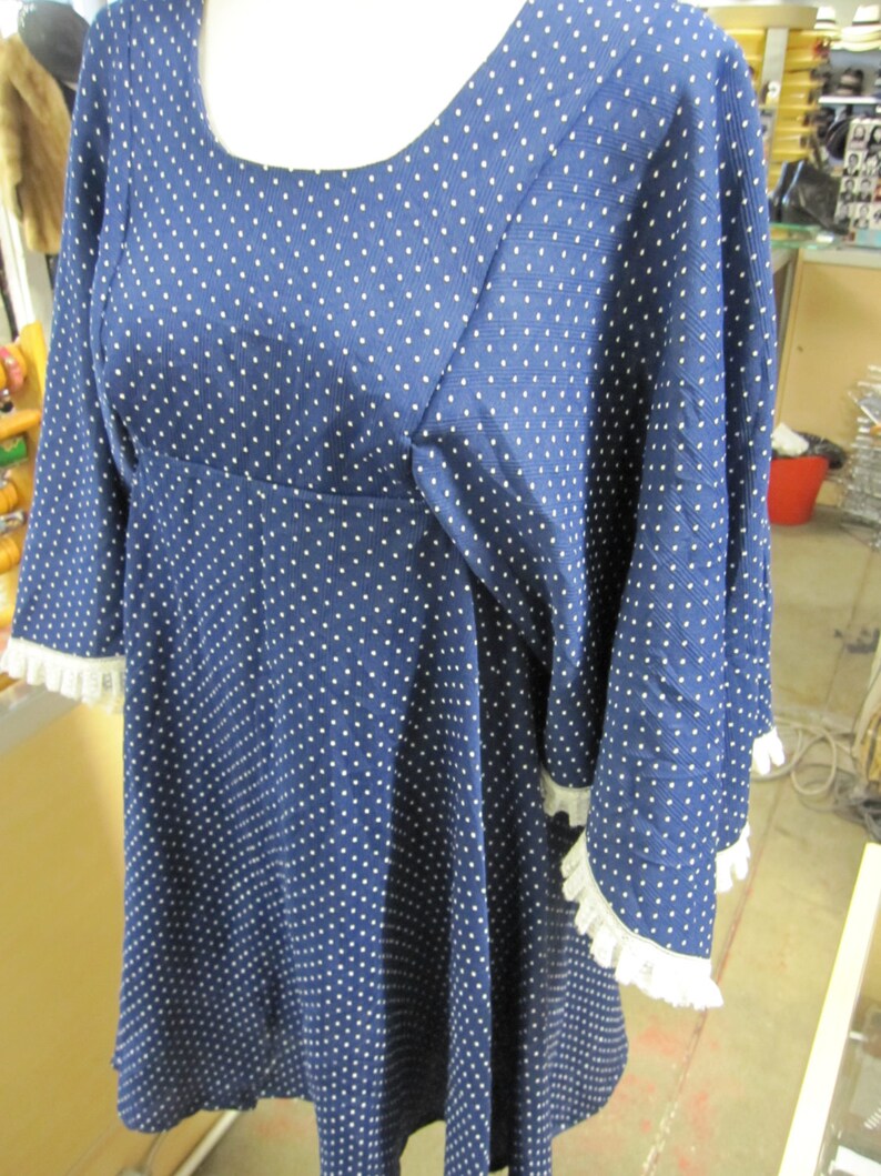 May include: A blue and white polka dot dress with a white lace trim on the sleeves. The dress has a scoop neck and a loose fit.