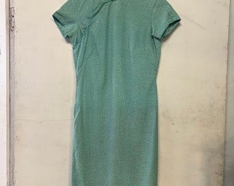 May include: A light green, short-sleeved, knee-length dress with a mandarin collar and a tie closure at the neckline.