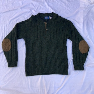 May include: A dark green long-sleeved sweater with a single button at the neck and brown leather elbow patches.