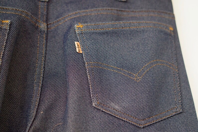 May include: Close-up of the back pocket of a pair of blue denim jeans. The pocket has a brown leather patch with the word "Levi's" printed on it.