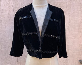May include: A black velvet cropped jacket with a satin collar and black sequin embellishments.