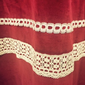 Puede incluir: Tela de terciopelo rojo con dos filas de encaje blanco. El encaje es un patr&oacute;n delicado con peque&ntilde;os c&iacute;rculos y cuadrados.