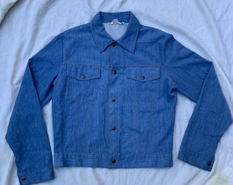 May include: A blue denim jacket with a button-up front and two chest pockets.
