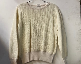 May include: A white quilted sweatshirt with a crew neck and long sleeves. The sweatshirt has a ribbed hem and cuffs.