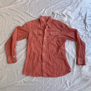 May include: A red and white gingham long-sleeved button-down shirt with two chest pockets.