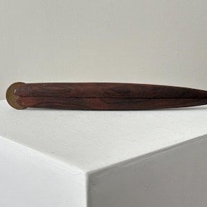 May include: A wooden box with a brass hinge. The box is closed and has a dark wood grain.