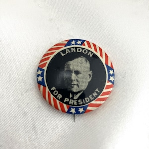 May include: A vintage political campaign button featuring a portrait of a man and the text "LANDON FOR PRESIDENT." The button has a red, white, and blue design with stars and stripes.