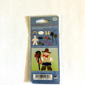 May include: A Mini Paperkins craft kit featuring a cowboy theme. The package includes paper cutouts of a cowboy, horse, and accessories. The text on the package reads "Round 'em Up Rosie rides the range and heads off into the sunset."