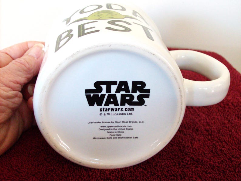 K&ouml;nnte beinhalten: Wei&szlig;e Keramiktasse mit dem Star Wars-Logo und dem Text "TODAY IS THE BEST DAY". Die Tasse hat einen abgerundeten Henkel und ein Charakterdesign. Der Boden der Tasse zeigt das Star Wars-Logo und die Website.