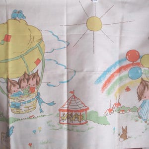 May include: Vintage fabric panel depicting a whimsical carnival scene. A yellow hot air balloon with three children floats above a fairground with a carousel, rainbow, and a child holding balloons. The artwork is in soft pastel colours.
